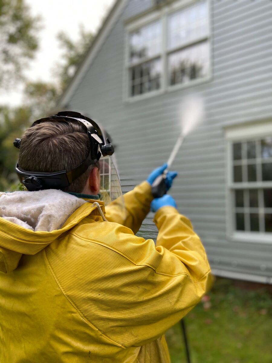 Pressure washing the vinyl siding of a house