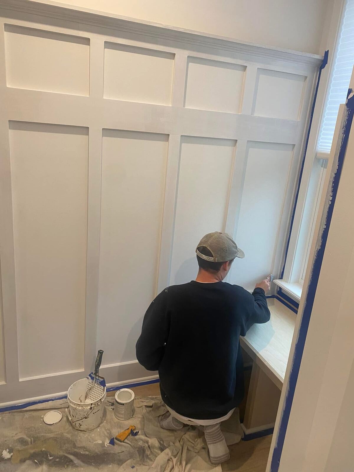 Painter finishing a white board-and-batten accent wall