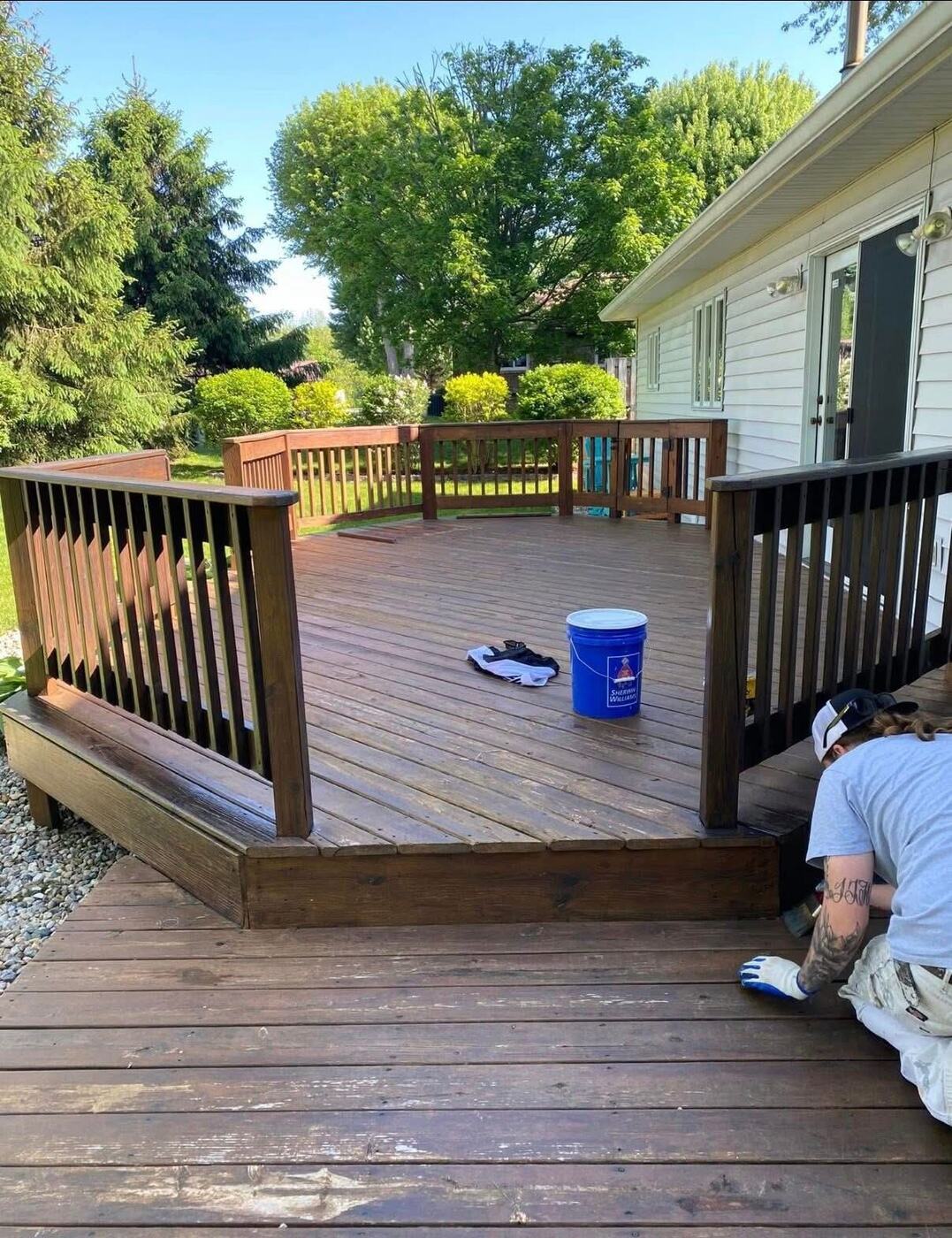 Painter staining a backyard deck and railings