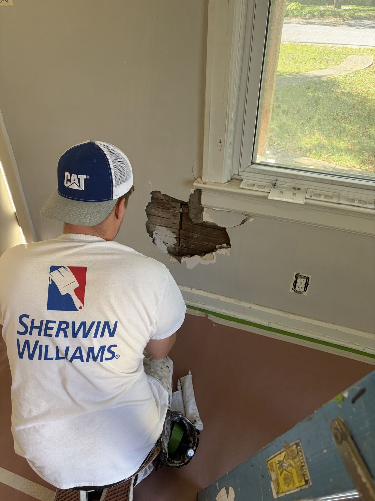 Paint Plus Indy painter repairing damaged drywall below a window before painting