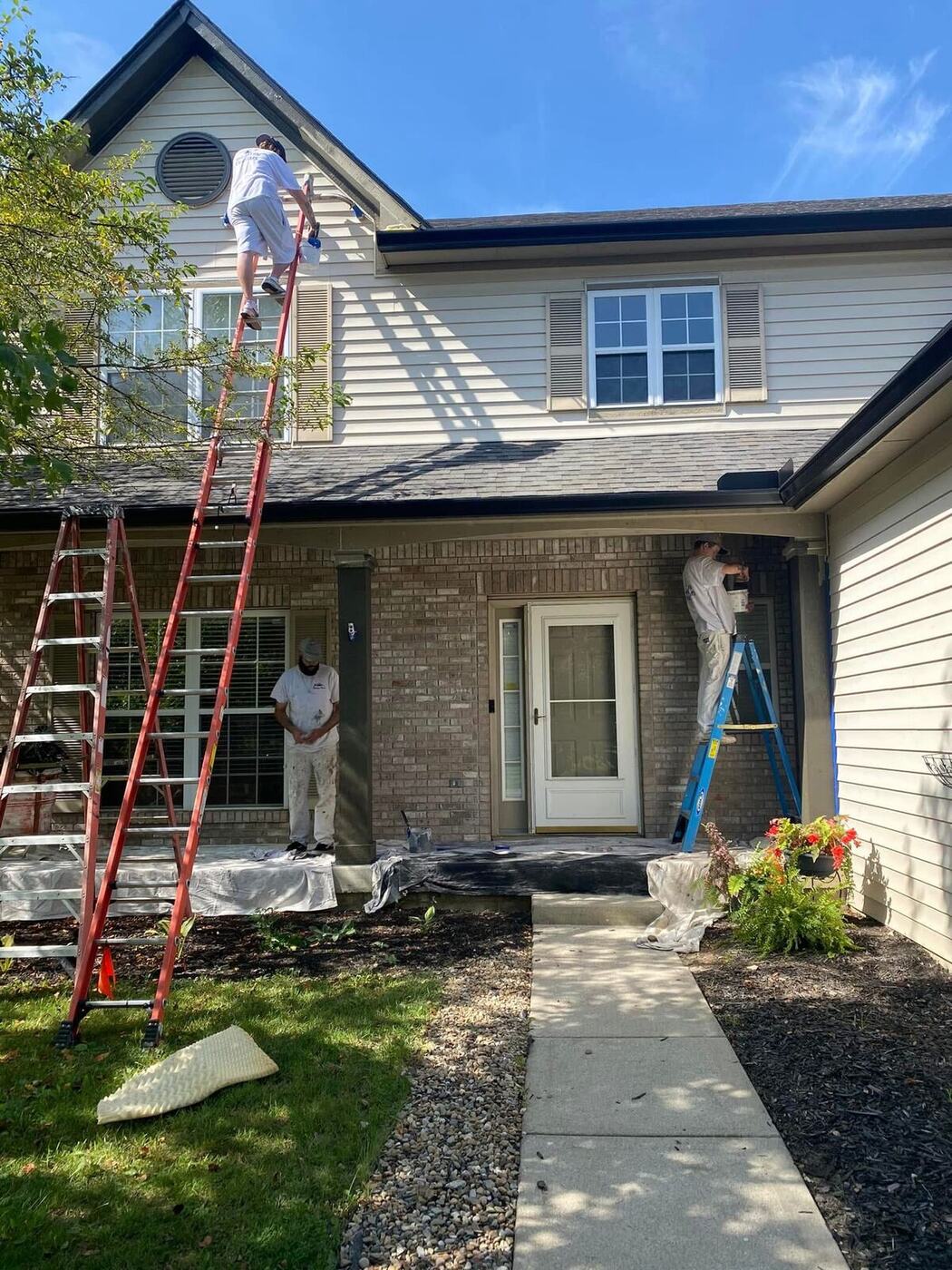 Paint Plus Indy crew on ladders painting the exterior of a two-story home