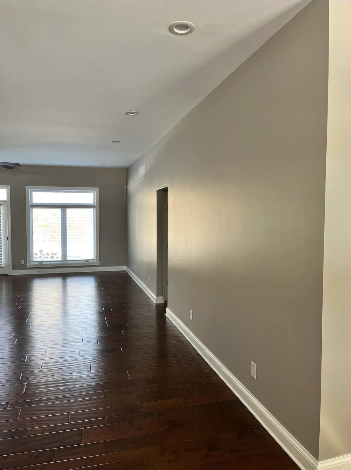 Long hallway with neutral painted walls and hardwood floors