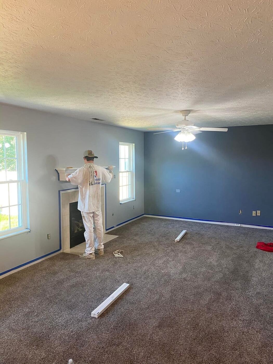 Painter at work in a living room with walls masked and floors protected