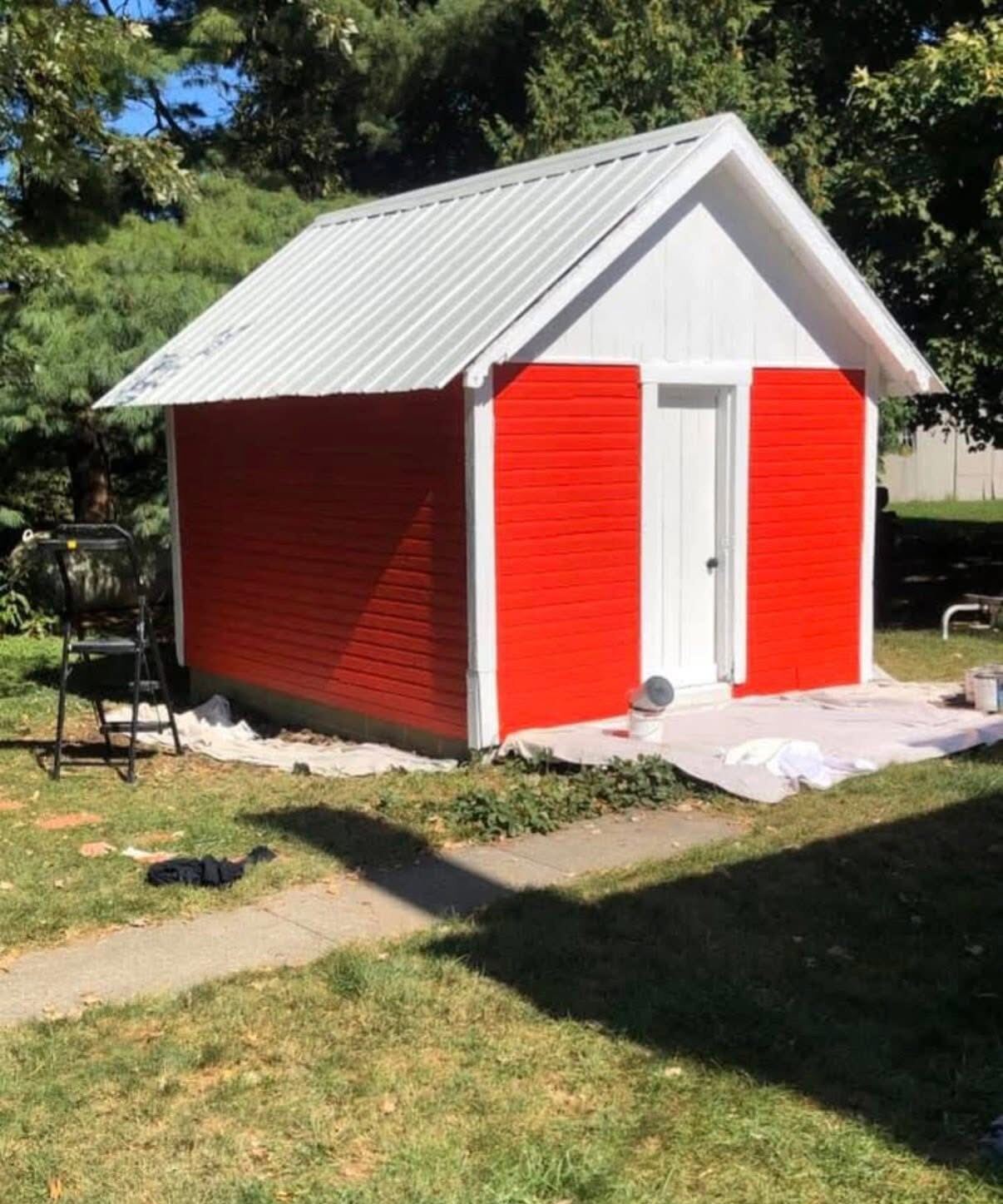 Same backyard shed after painting in bright red with white trim