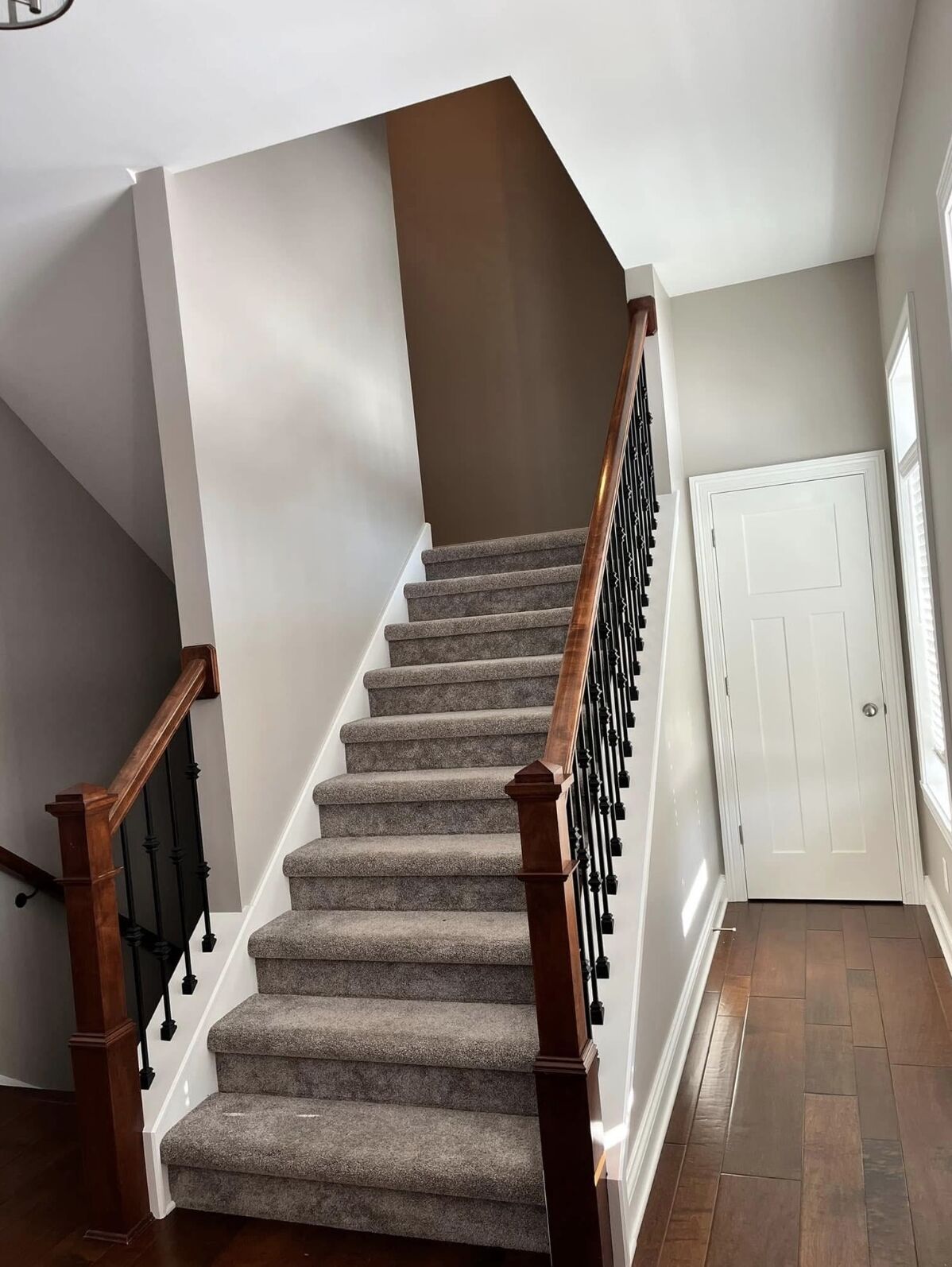 Carpeted staircase with freshly painted walls and white trim